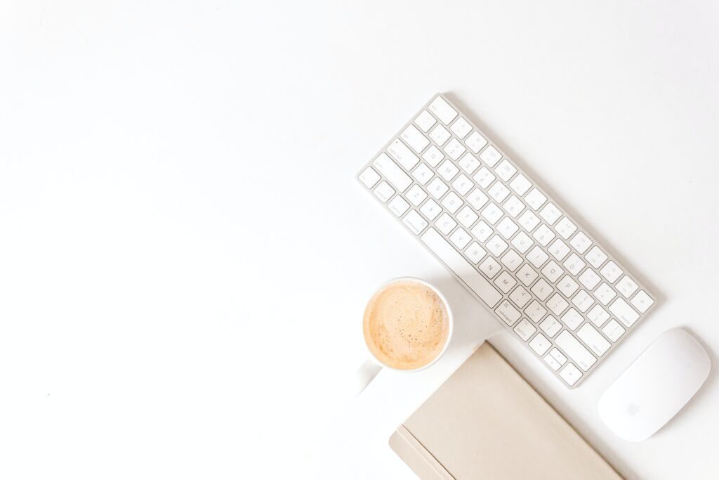 MacBook keyboard, coffee, MacBook mouse and notebook