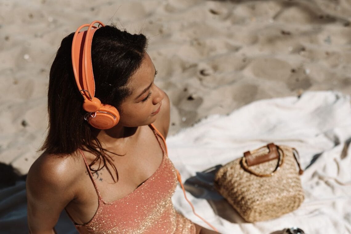 woman on a beach listening to a podcast