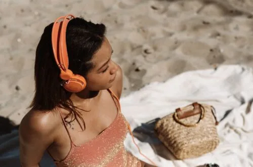woman on a beach listening to a podcast