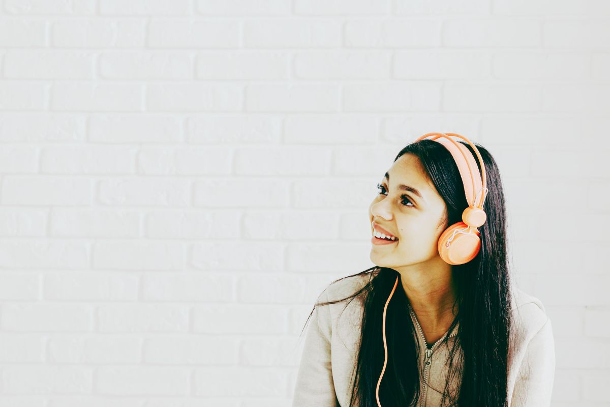 Girl listening to a podcast with pink headphones