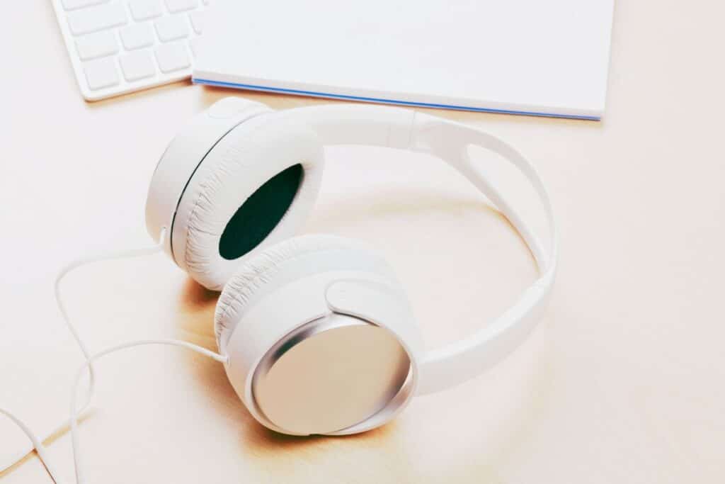 Why do podcasters wear headphones? White headphones on a beige desk