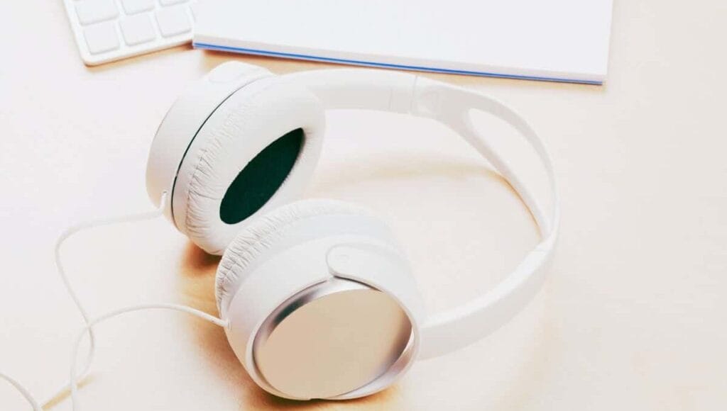 Why do podcasters wear headphones? White headphones on a beige desk