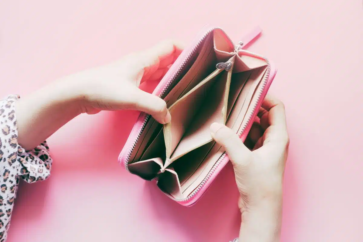 woman opening an empty wallet indicating no money