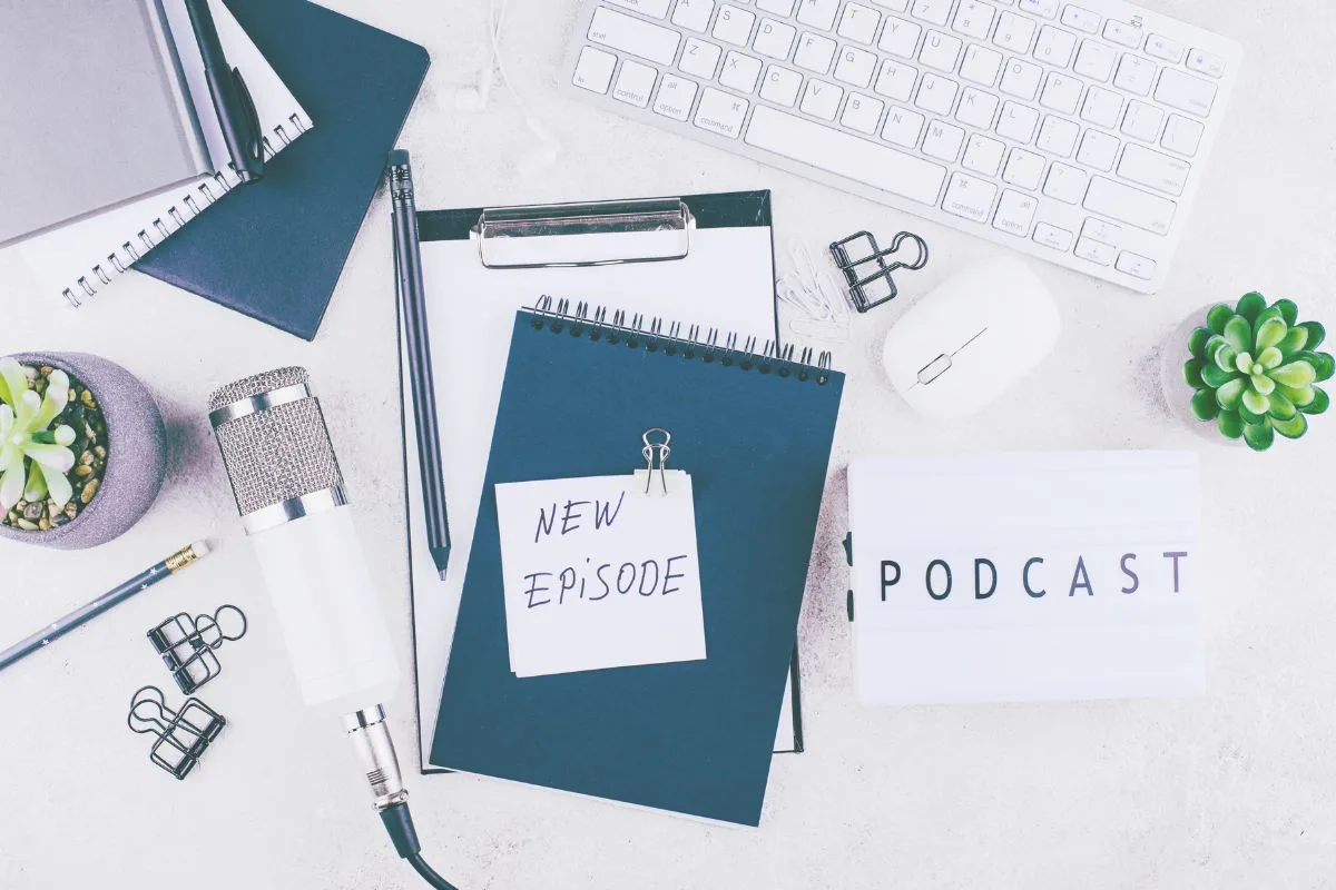 Podcast episode titles for new podcast episodes. Written on notebook on a white desk. microphone on desk and keyboard