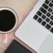 cup of coffee next to an open MacBook