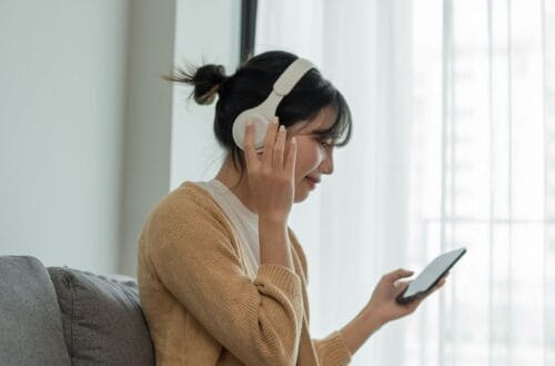 female wearing headphones and listening to a podcast on a mobile phone