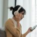 female wearing headphones and listening to a podcast on a mobile phone