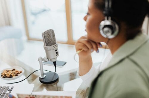 woman speaking into a microphone and wearing headphones whilst hosting a podcast interview