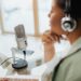 woman speaking into a microphone and wearing headphones whilst hosting a podcast interview